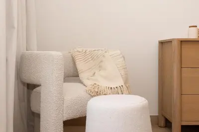 a white chair with a throw pillow and a stool at HiGuests - Experience Coastal Elegance at La Rive 2 in La Mer in Dubai