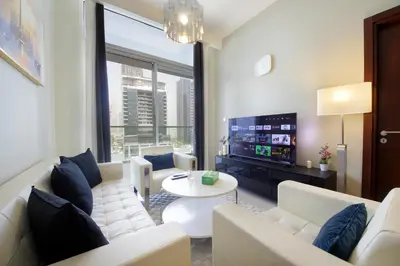 a living room with a white couch and a tv at Wecation Damac Vera - Business Bay in Dubai