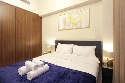 a bedroom with a bed with two rolled towels on it at Wecation Damac Vera - Business Bay in Dubai