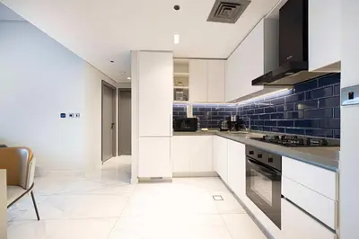 a kitchen with white cabinets and blue tiles at MajeStay - MAG Living in Dubai