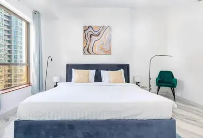 a bedroom with a large bed and a green chair at Ahlan Premium Luxury Marina Cityview JBR in Dubai