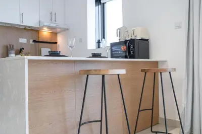 a kitchen with two bar stools and a microwave at SuCasa in Dubai