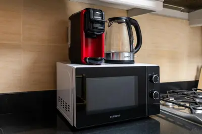 a coffee maker is sitting on top of a microwave at Stunning studio at sports city in Dubai