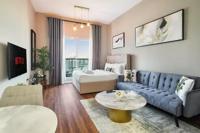 a living room with a couch and a bed at Stunning studio at sports city in Dubai