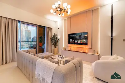 a living room with a large couch and a tv at Grande Signature Deluxe Next to Dubai Opera by BMS in Dubai