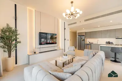 a living room with a large couch and a kitchen at Grande Signature Deluxe Next to Dubai Opera by BMS in Dubai