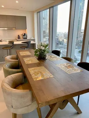 a large wooden table with chairs and a kitchen at Grande signature residence Smart Burj khalifa Fountains view large 3 bedroom hall 4 bathroom view burj khalifa Fountains from hall and rooms balcony in Dubai