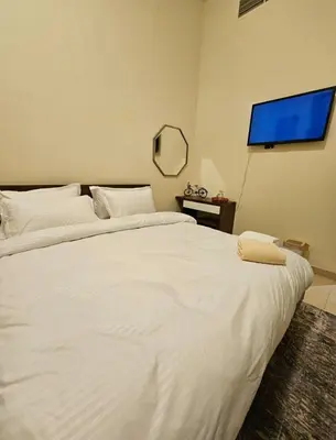 a bedroom with a large white bed with a flat screen tv at Room with bathroom near beach walk la mer beach Oima leasing property in Dubai