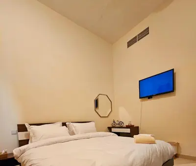a bedroom with a bed and a flat screen tv on the wall at Room with bathroom near beach walk la mer beach Oima leasing property in Dubai