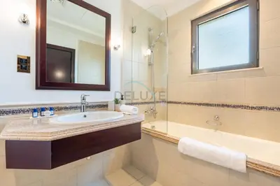 a bathroom with a sink and a mirror and a tub at Beach Access Villa with Backyard in Prime Location in Canal Cove, Palm Jumeirah by Deluxe Holiday Homes in Dubai