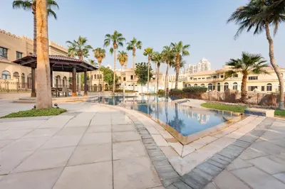 a swimming pool in a courtyard with palm trees at Beach Access Villa with Backyard in Prime Location in Canal Cove, Palm Jumeirah by Deluxe Holiday Homes in Dubai