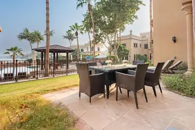 a patio with a table and chairs and a fence at Beach Access Villa with Backyard in Prime Location in Canal Cove, Palm Jumeirah by Deluxe Holiday Homes in Dubai