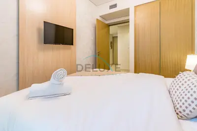 a bedroom with a white bed and a tv on a wall at Limited Time Offer Tranquil 1BR in Business Bay by Deluxe Holiday Homes in Dubai