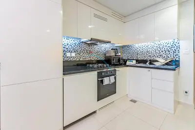 a kitchen with white cabinets and a stove at Limited Time Offer Tranquil 1BR in Business Bay by Deluxe Holiday Homes in Dubai