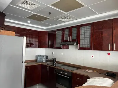 a kitchen with brown cabinets and a white tiled ceiling at Opal Tower in Dubai
