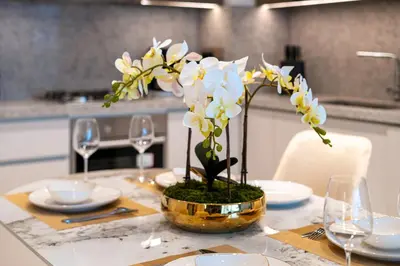 a table with a vase with white flowers on it at Exclusive Beachfront 2 Bed with Pool & Palm View in Dubai