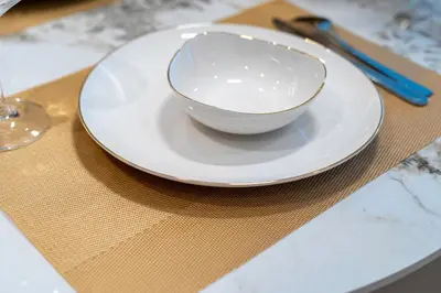 a white bowl sitting on a plate on a table at Exclusive Beachfront 2 Bed with Pool & Palm View in Dubai