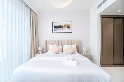 a bedroom with a large white bed with two towels at Exclusive Beachfront 2 Bed with Pool & Palm View in Dubai