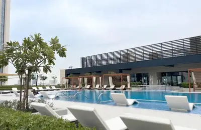 a swimming pool with white lounge chairs and a building at 1bedroom Apartment With Stunning view Creek Harbour in Dubai
