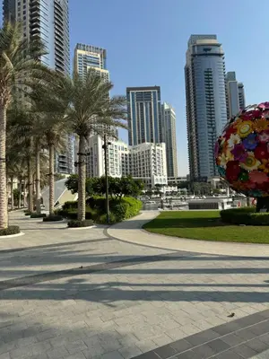 a park with palm trees and buildings in the background at 1bedroom Apartment With Stunning view Creek Harbour in Dubai