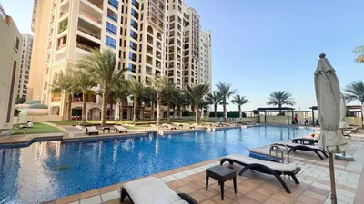 a large swimming pool with palm trees and buildings at Marina Haven I Waterfront I Pool I Gym and Sauna in Dubai