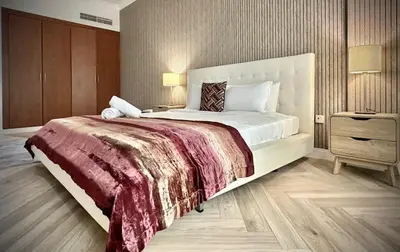 a bedroom with a large bed and a wooden floor at Modern 1BR Retreat with Balcony in Vibrant JVC by Bhavan Vacation Homes in Dubai
