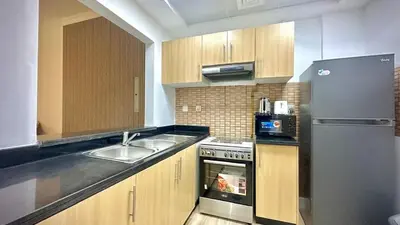 a kitchen with a sink and a stainless steel refrigerator at Modern 1BR Retreat with Balcony in Vibrant JVC by Bhavan Vacation Homes in Dubai