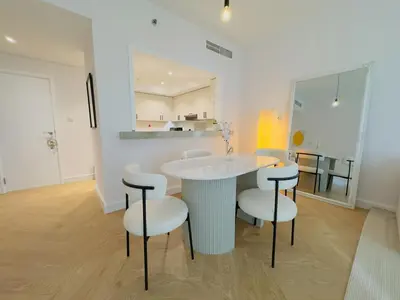 a white kitchen with a table and stools at Burj KhalifaView Luxury 1-Bedroom Apartment in Dubai