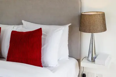 a red pillow sitting on a bed next to a lamp at Family Friendly - 2BR & Maid's Room in The Springs 10 - Allsopp & Allsopp in Dubai
