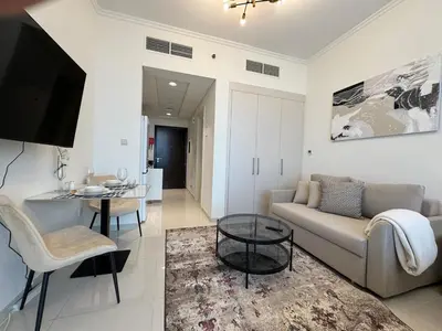 a living room with a couch and a table at ASHRI Studio in Carson C, Damac Hills 1 in Dubai