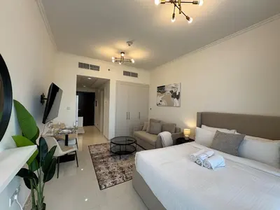 a bedroom with a bed and a living room at ASHRI Studio in Carson C, Damac Hills 1 in Dubai