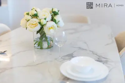 a vase of white flowers and a wine glass at Mira Holiday Homes - Newly 2 bedroom in La Sirene, Port De La Mer in Dubai