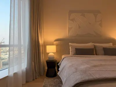 a bedroom with a bed with a lamp and a window at Signature Studio JLT in Dubai