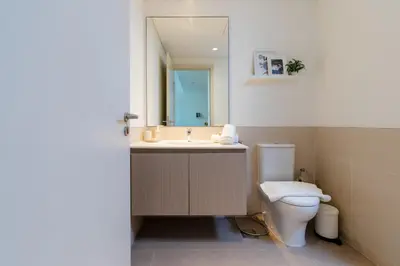 a bathroom with a toilet and a sink and a mirror at Comfortable Stylish Haven - Great Community in Dubai
