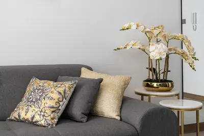 a gray couch with pillows and a vase with flowers at SIMPLY COMFORT in Missoni Top Floor with Sea, Canal and Burj Khalifa Views in Dubai