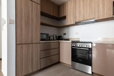 a kitchen with wooden cabinets and a stove top oven at SIMPLY COMFORT in Missoni Top Floor with Sea, Canal and Burj Khalifa Views in Dubai