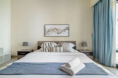 a bedroom with a large white bed with a blue rug at GuestReady - Magnificent stay with lake view in Dubai