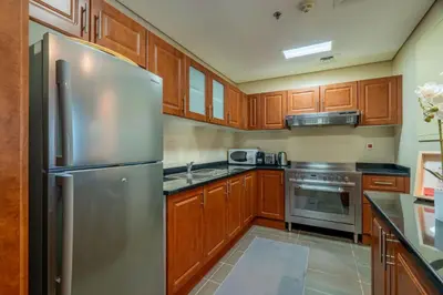 a kitchen with wooden cabinets and a stainless steel refrigerator at GuestReady - Magnificent stay with lake view in Dubai