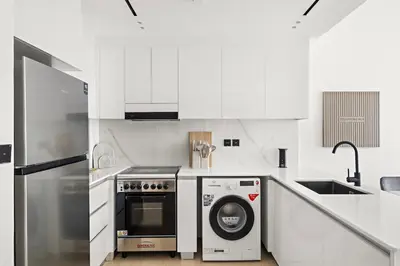 a white kitchen with a dishwasher and a washer at Stunning 1 br modern luxury residence at JVC in Dubai