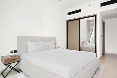 a white bedroom with a large bed and a mirror at Stunning 1 br modern luxury residence at JVC in Dubai