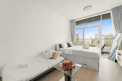 a bedroom with two beds and a large window at Chic JVC Studio in Dubai - Pool, Gym, Free Parking, City Views & Prime Location in Dubai