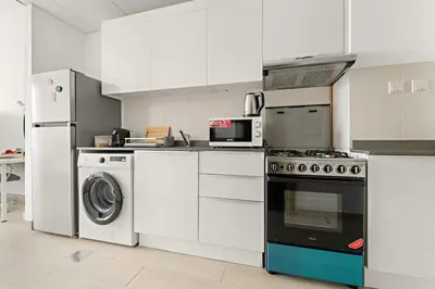 a kitchen with a stove and a washer and dryer at Chic JVC Studio in Dubai - Pool, Gym, Free Parking, City Views & Prime Location in Dubai
