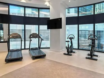 a gym with three tread machines in a room with windows at 2BR Jumeirah Gate 1, Marina Skyline View in Dubai