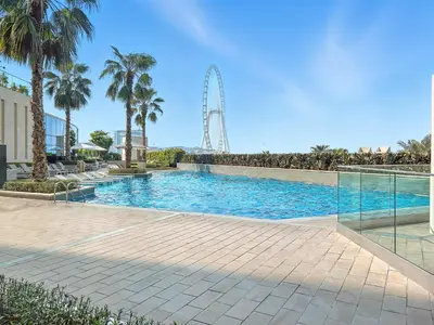 a swimming pool with a ferris wheel in the background at 2BR Jumeirah Gate 1, Marina Skyline View in Dubai