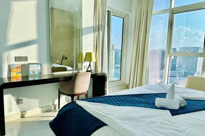 a hotel room with a bed and a desk with a window at Vserve Stylish Suite 1 BR with Burj Khalifa and Canal view in Dubai
