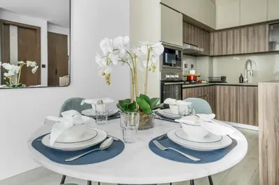 a white dining room table with plates and dishes on it at Comfy 1BR w Cinema Room Business Centre Pool Table and Sauna in Dubai