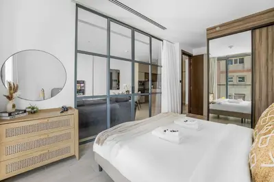 a bedroom with a large white bed and a mirror at Comfy 1BR w Cinema Room Business Centre Pool Table and Sauna in Dubai