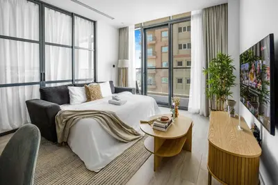 a hotel room with a bed and a table and windows at Comfy 1BR w Cinema Room Business Centre Pool Table and Sauna in Dubai