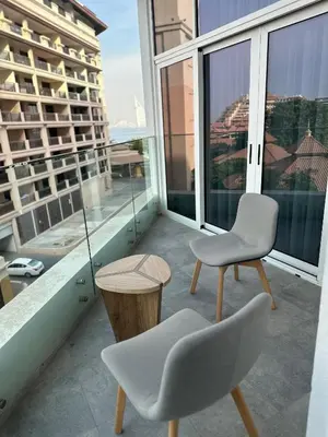 a balcony with two chairs and a table and windows at Azizi Mina in Dubai