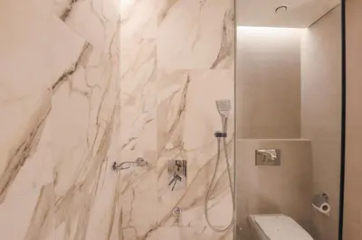 a bathroom with a shower with a marble wall at Stunning 1BR in heart of Dubai Marina in Dubai
